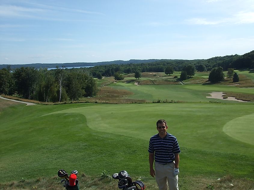 Golfer standing in front of 9th green at Crystal Downs Country Club in Frankfort, Michigan.