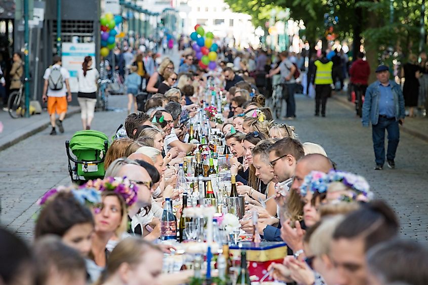 Long table with lots of people eating and drinking together. The Day of City Celebration in centre of Helsinki. Finnish your dinner under the sky.