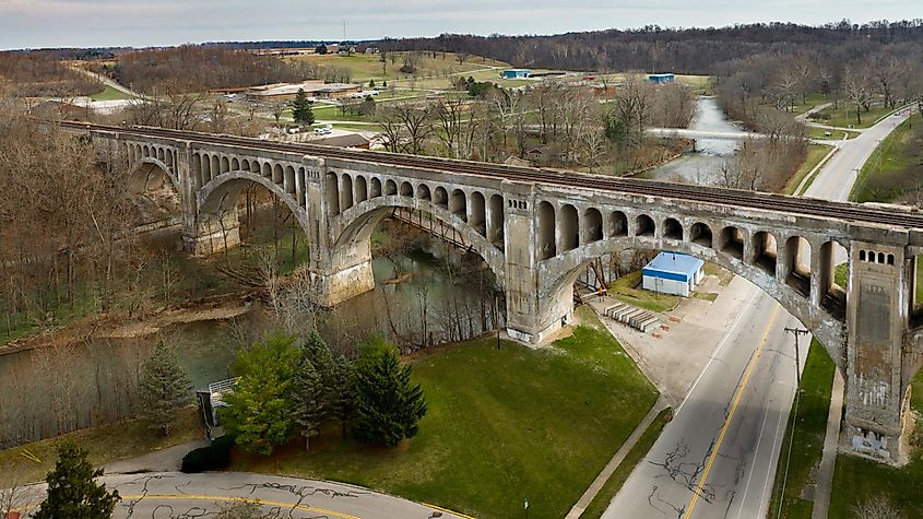 Aerial view of a historic arched bridge with train tracks over a road in Lima, Ohio, blending early 20th-century engineering with the modern landscape.