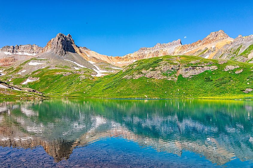 Landscape view of green meadow and Ice lake water reflection near Silverton, Colorado in August 2019 summer on summit with snow and peak