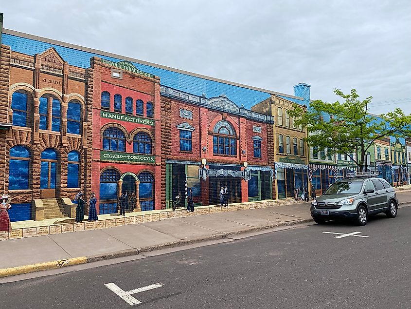 A colorful mural depicting 19th century Ashland, Wisconsin dominates the entire side of a building.