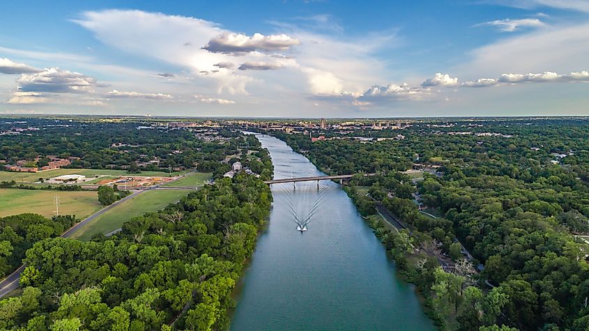 Aerial view of a boat sailing down the Brazos River and the skyline of the city of Waco, Texas