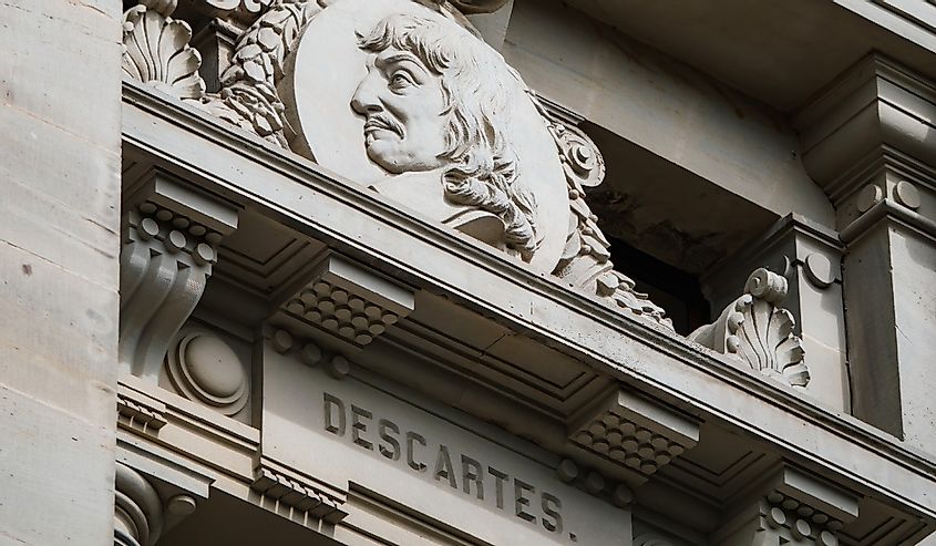 A low angle view of a statue of Rene Descartes against the historic building exterior, showcasing its intricate architecture and craftsmanship.