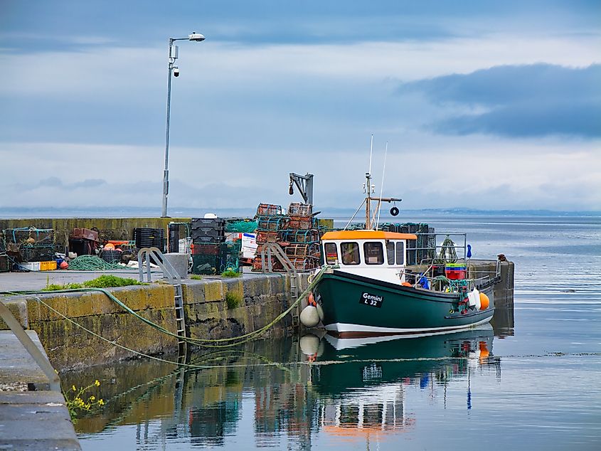A lively fishing boat rests beside the bustling quay in Ballyvaughan, Ireland