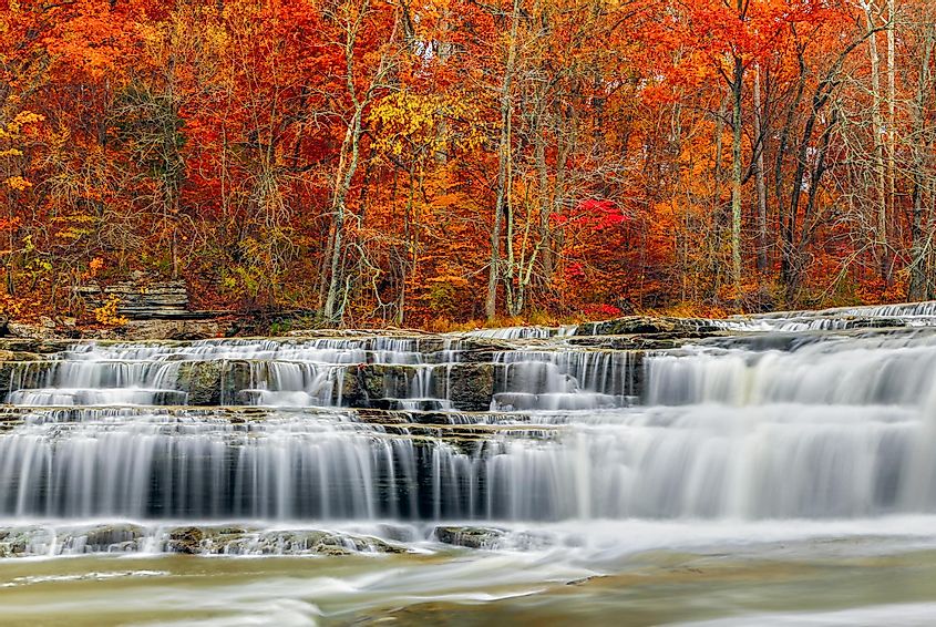 Whitewater pours over rock ledges at Indiana's Upper Cataract Falls with beautiful, colorful fall foliage.