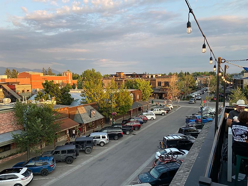 A cloudy, pastel sunset seen from a brewery's rooftop patio with the Old West main street of Whitefish, Montana below.