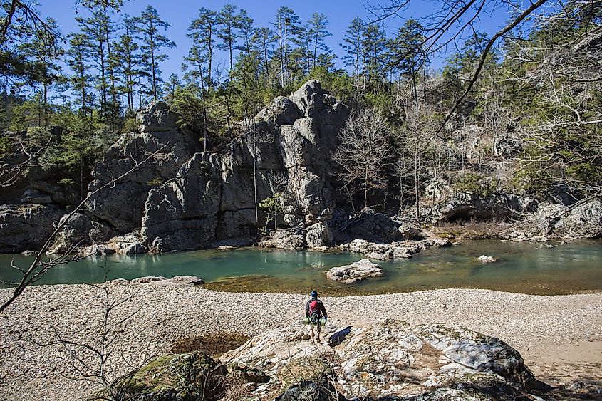 A hiker exploring the Ouachita Mountains with flowing water and mountains.