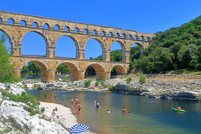 Ancient arches of Pont du Gard and people swimming on the river near Nimes, France