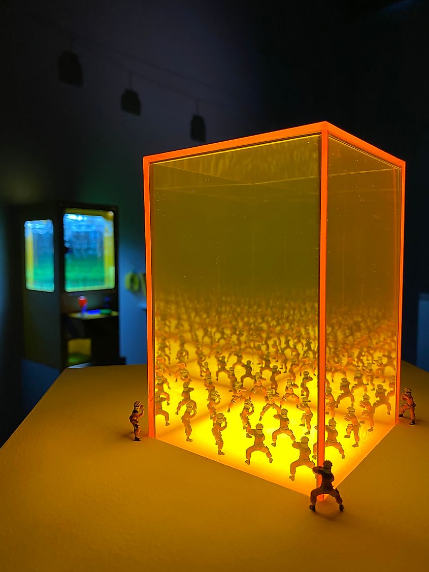 A dark art gallery illuminated by miniature models that exude a repeating, infinity effect.