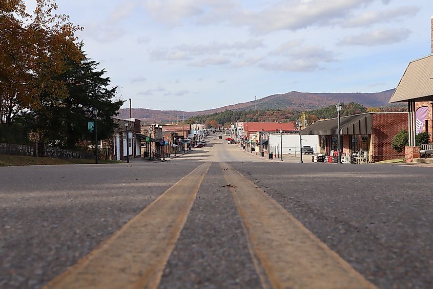 A street-level view down Main Street (Mena Street), Mena, Arkansas with autumn colors on Rich Mountain in the background, via Gina Santoria / Shutterstock.com