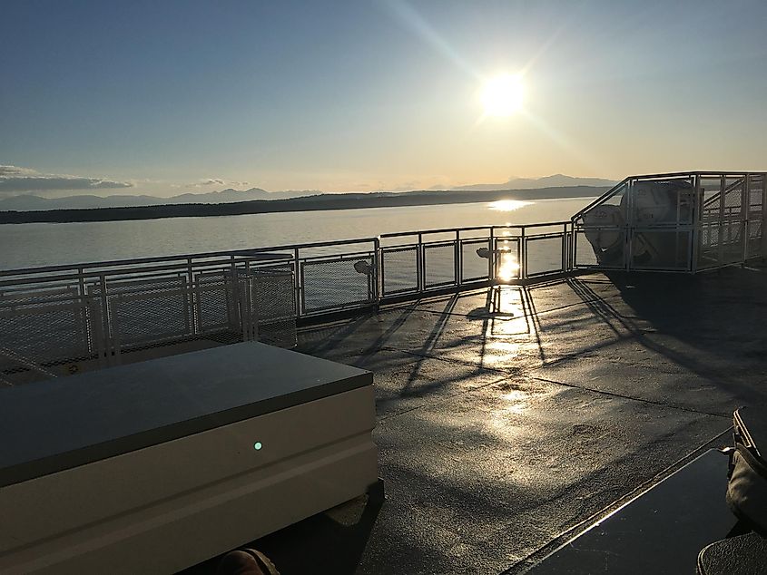 The view from the deck of a ferry while the sun sinks low in the sky 