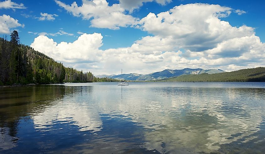 Panoramic view of puffy white clouds reflecting on the surface of a tranquil Alturas Lake in the Rocky Mountains of Idaho