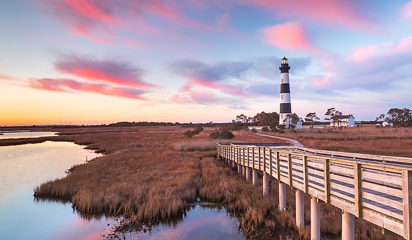 Clouds stream like pink ribbons in the sky over the marsh and lighthouse on Bodie Island on the Outer Banks of North Carolina.