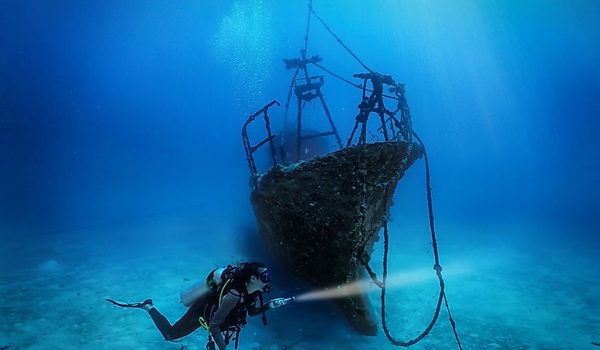 Female diver explores a shipwreck. 