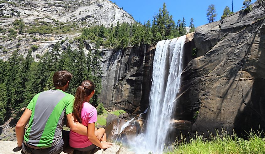 Hikers resting in Yosemite National park enjoying view of beautiful waterfall, Vernal Fall.