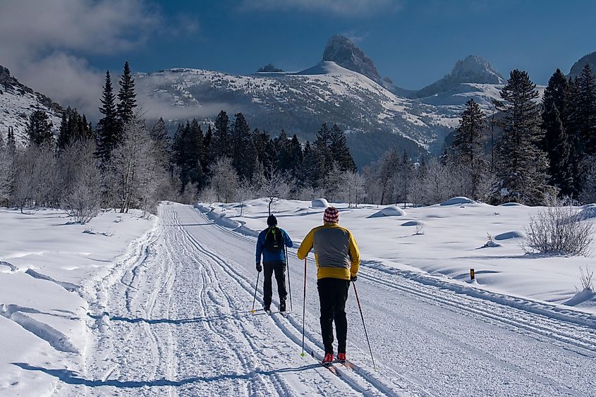 Two men classic Nordic skiing in Teton Canyon near Driggs Idaho and Alta, Wyoming, Grand Teton in distance.