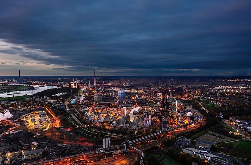 Aerial night skyline view of ThyssenKrupp steel production plant with industrial blast furnace in the foreground in Duisburg, Germany.