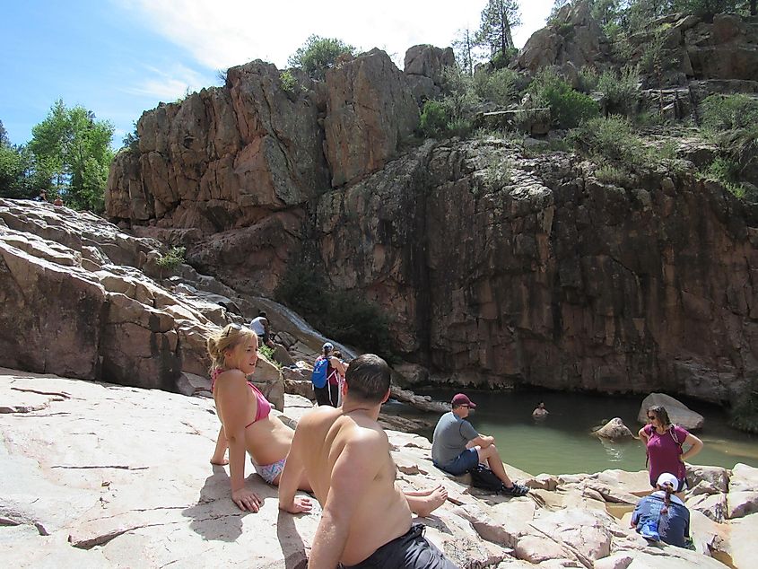 The Ellison Creek waterfall with tourists and locals sitting and swimming at the Water Wheel Falls hiking trail
