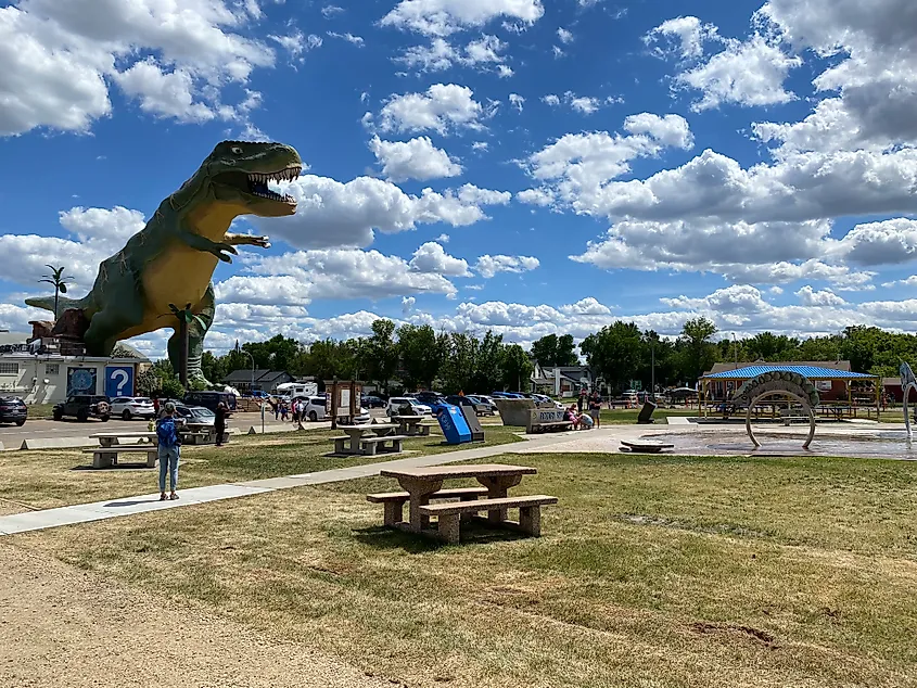 The 25-meter-tall, green and yellow T-Rex known as "Trya" looms large in front of a cloudy blue sky.