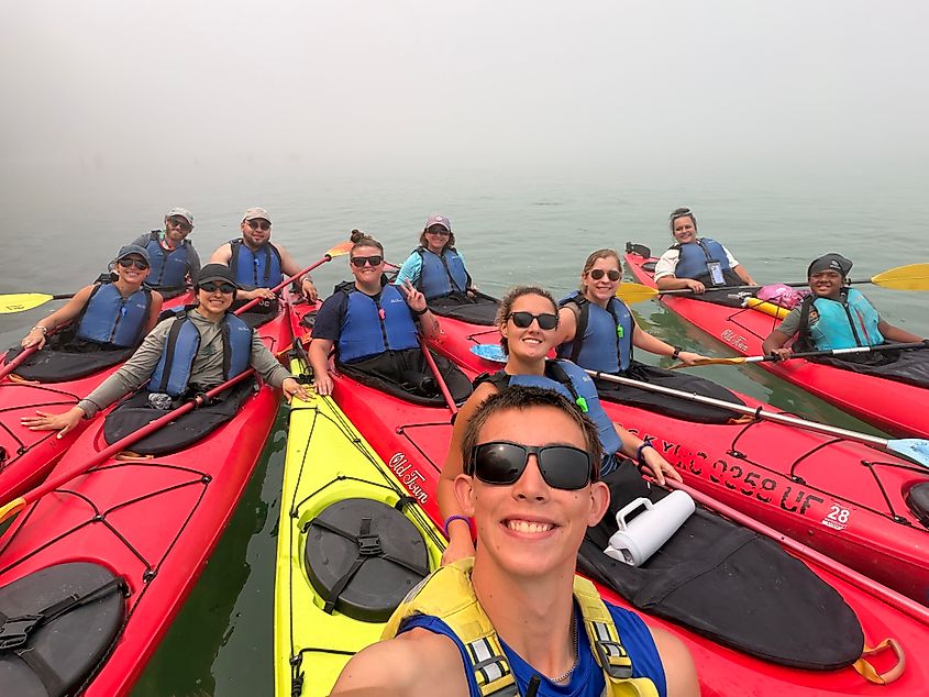 A group of kayakers pose for a selfie while out on the foggy waters.