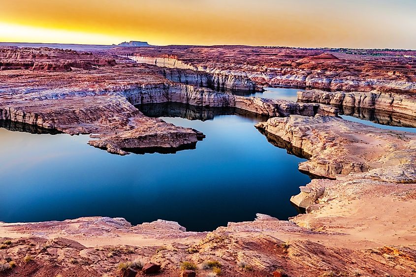 Lake Powell surrounded by red sandstone canyon walls.