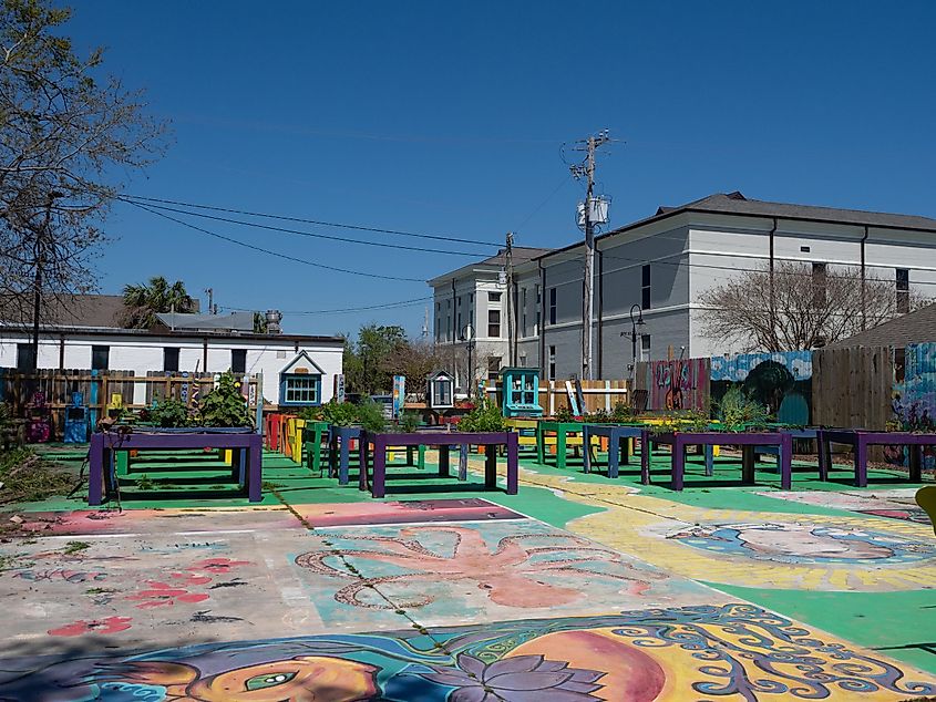 Ruth's Roots Community Garden in Bay St. Louis, Mississippi with outdoor murals painted on the cement slabs in the garden and raised planters in the background.
