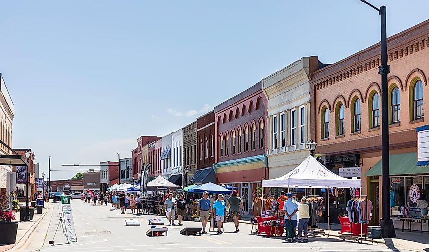 Summer street festival in Elkin, NC, with vendors under canopies on a hot day.