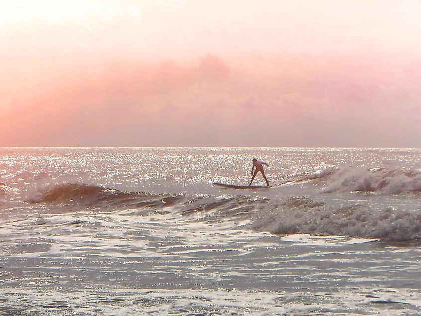 A young surfer riding a wave at sunrise on Folly Beach, South Carolina