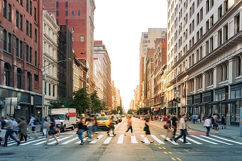 Crowds of people walking through a busy crosswalk at the intersection of 23rd Street and Fifth Avenue in Midtown Manhattan, New York City