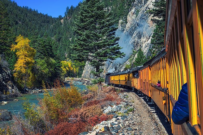 Historic steam engine train travels from Durango to Silverton through the San Juan Mountains along the Animas River in Colorado, USA.