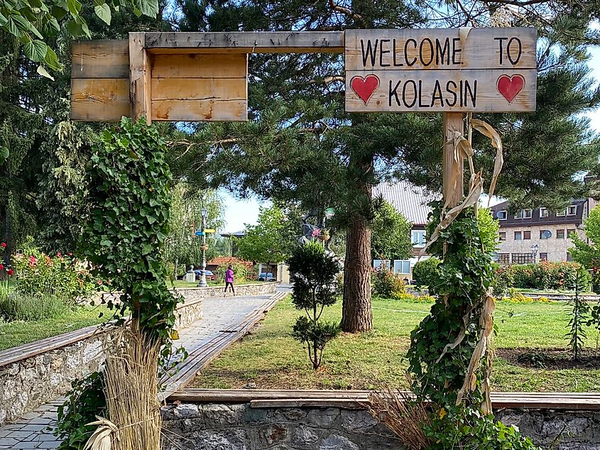 A green city park with a wooden "Welcome to Kolasin" sign 