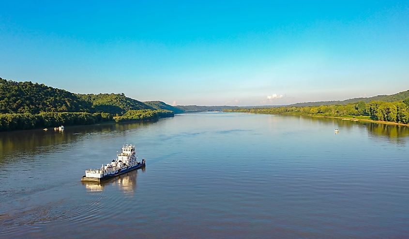 An aerial view captures a tugboat navigating the Ohio River between Indiana and Kentucky.