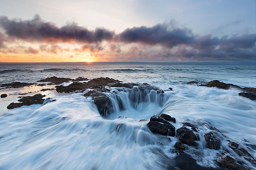 Water rushes into Thor's Well on the Pacific Ocean as the sun sets over Oregon.