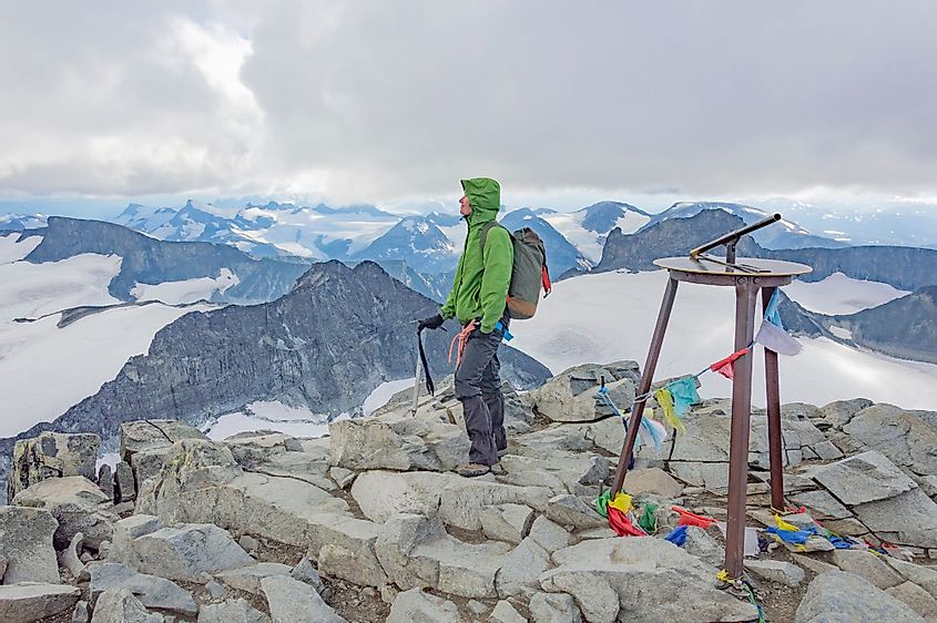 A young woman alpinist standing on the top of the Galdhopiggen mountain summit in Norway