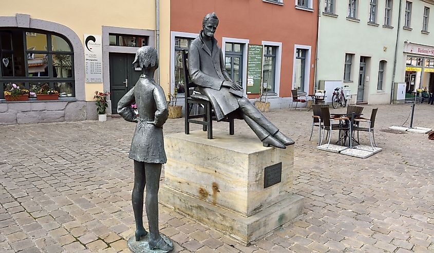 Friedrich Nietzsche memorial on the Markt square in Naumburg, with cafe tables and cafe in the background.
