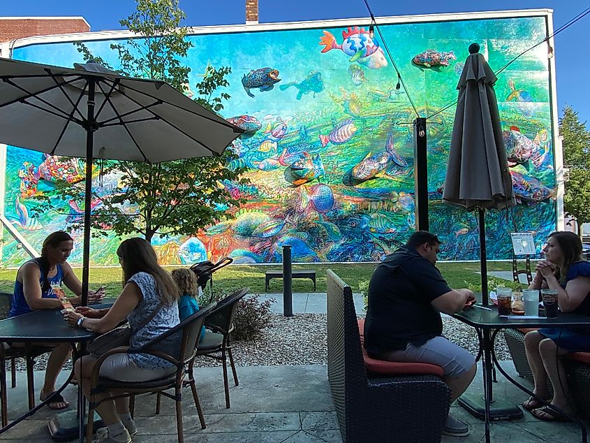 Tables full of people seated in front of a massive, colorful fish mural on the opposite wall