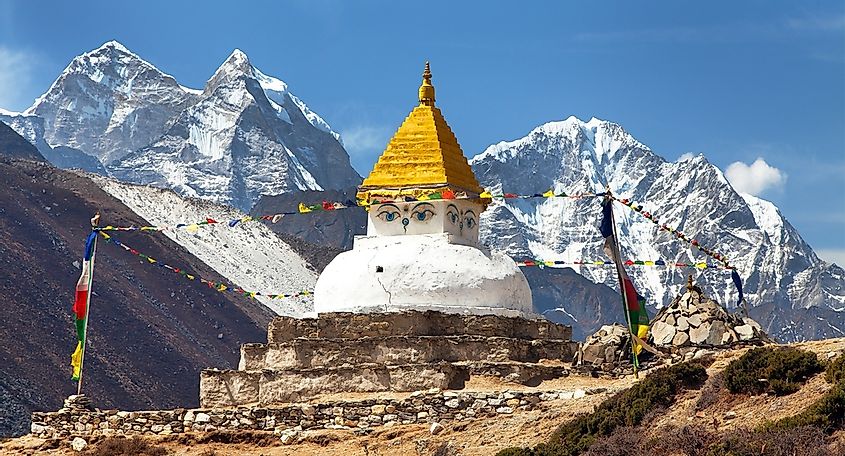 A stupa near Dingboche village adorned with prayer flags and the stunning backdrop of Mounts Kangtega and Thamserku.