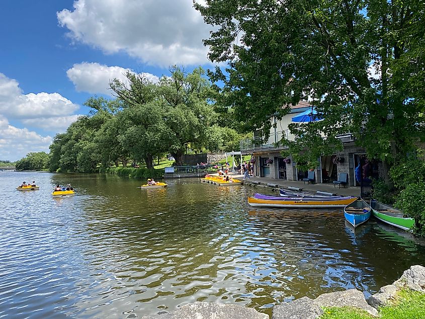 Peddle boats and canoes out on a lush river on a sunny afternoon.