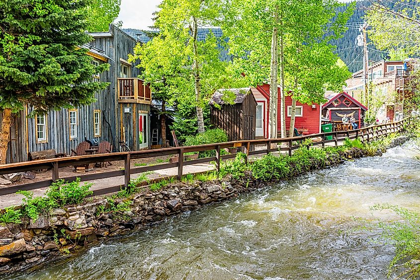 Colorado village houses by coal creek river in summer with vintage mountain architecture and aspen trees on sunny day, via Kristi Blokhin / Shutterstock.com