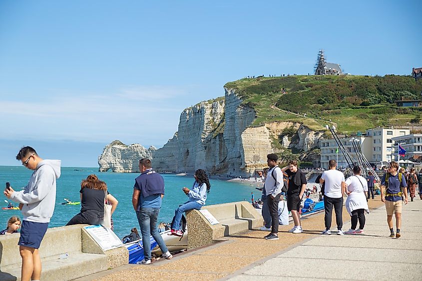 Étretat, France: Tourists enjoy sunshine on the beach with cliff in the backgound