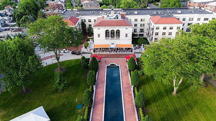 Aerial view of a landscaped property in Morristown, New Jersey, featuring a long reflecting pool, formal lawns, mature trees, and a large building in summer.
