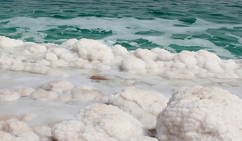 Dead Sea salt crystals on the shoreline of Israel. Beautiful turquoise water coastline of the Dead Sea with beautiful salt crystals