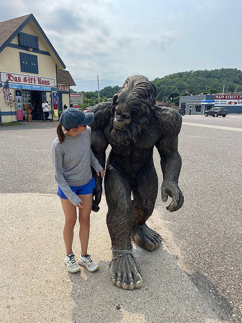 A woman eyes up a Bigfoot statue outside of a gift shop. 
