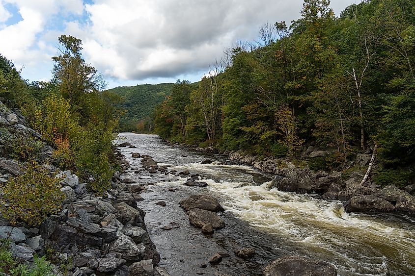 A landscape of Deerfield River with wood trees with cloudy sky in Massachusett.