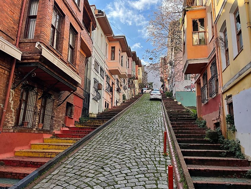 Rainbow colored steps lead up a steep cobblestone street.