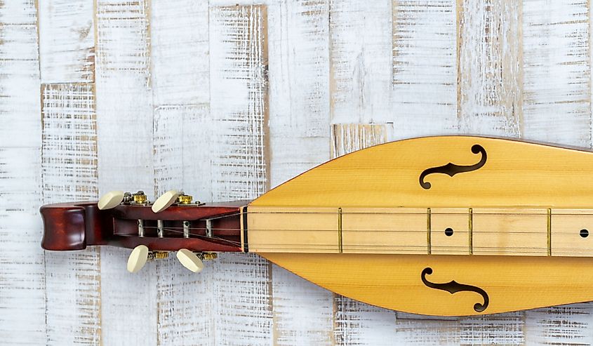 Detail view of an Appalachian mountain dulcimer musical instrument on a rustic white wooden background