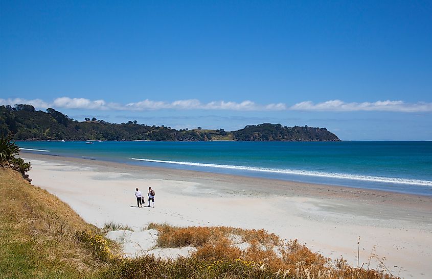 Tourists walking down Onetangi Beach in Onetangi, New Zealand.