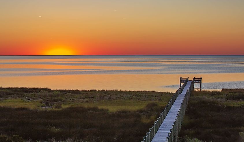 Coastal view of sunset over Pamlico Sound and boardwalk in Salvo, North Carolina on the Outer Banks.