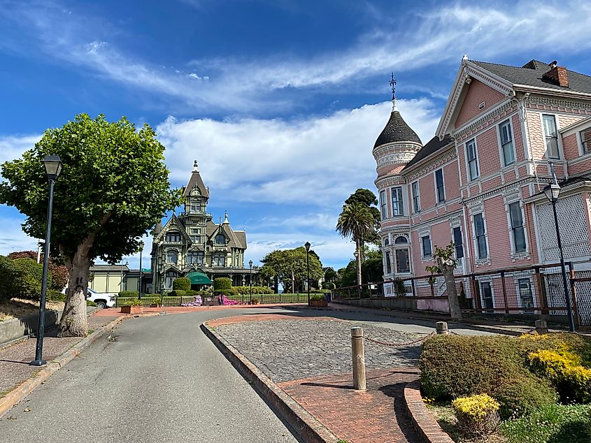 A pink Victorian mansion looks across at another ornate, Victorian era estate.