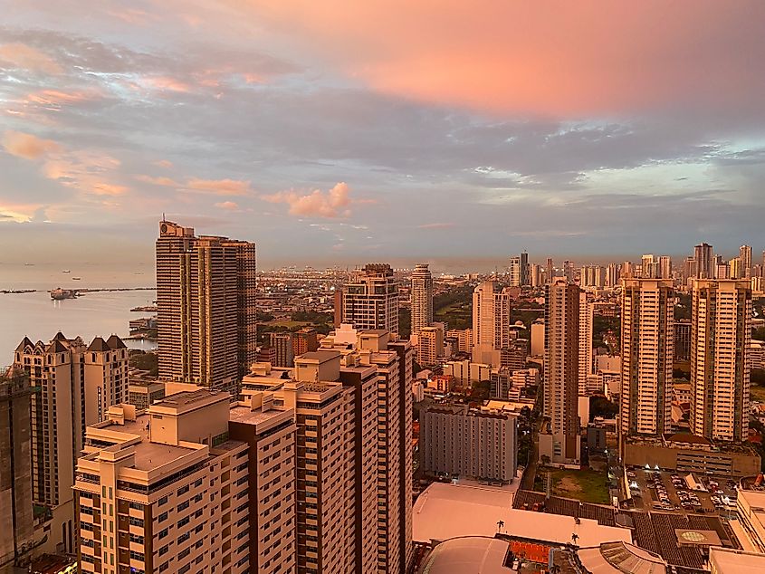 The large coastal city of Manila as seen from above during a pastel sunset.